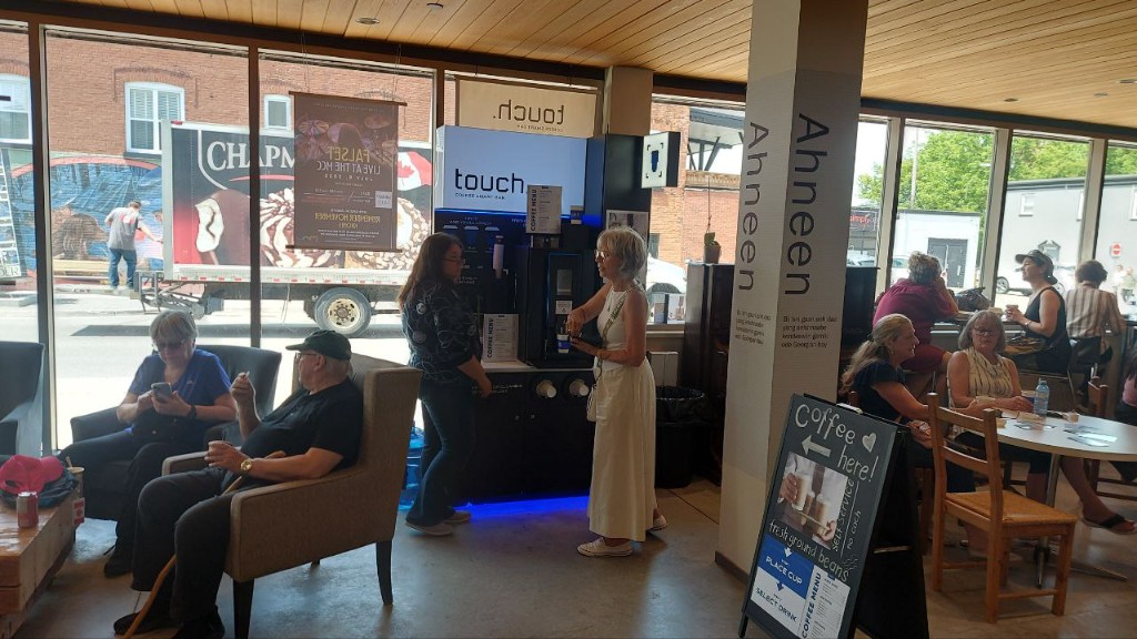 Guests at a Touch Coffee bar in a bright café, one person pouring a drink.